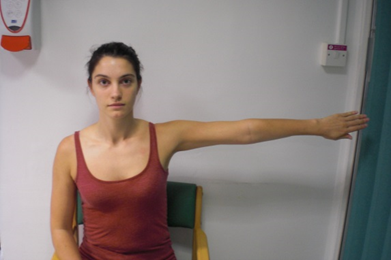 Patient seated with arm outstretched to one side, palm facing behind them.