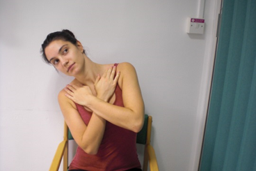 Photo of a seated patient in the same arms folded position with their torso leant over to one side.