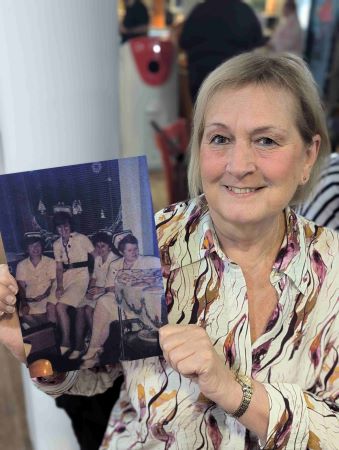 a woman holding an old photo of a group of young nurses