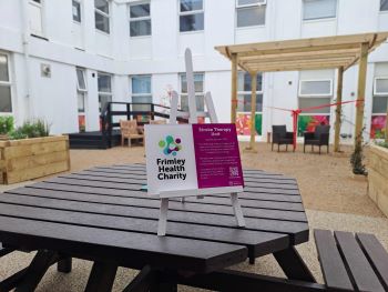 outdoor picnic table with Frimley health charity sign on top