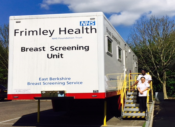 Photo of mobile breast screening unit- a large trailer raised on supports. A set of 7 stairs leads to the entrance.