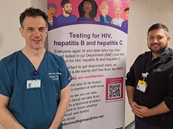 Dr Patrick Aldridge and Avi (Nishan) Khanal, standing either side of a poster for the new blood screening project.